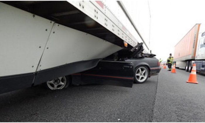 Une Mustang accidentée sous une semi-remorque où elle s'est coincée avant d'être traînée sur 800 mètres sur une autoroute en Indiana le 12 mai 2019. (Police d'État de l'Indiana)