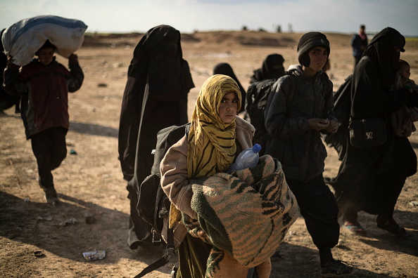 Des femmes et des enfants ayant quitté les rangs de l’État islamique (EI) se rendent aux Forces démocratiques syriennes le 6 mars 2019, près de Baghouz, dans le nord-est de la Syrie. Crédit : DELIL SOULEIMAN/AFP/Getty Images.