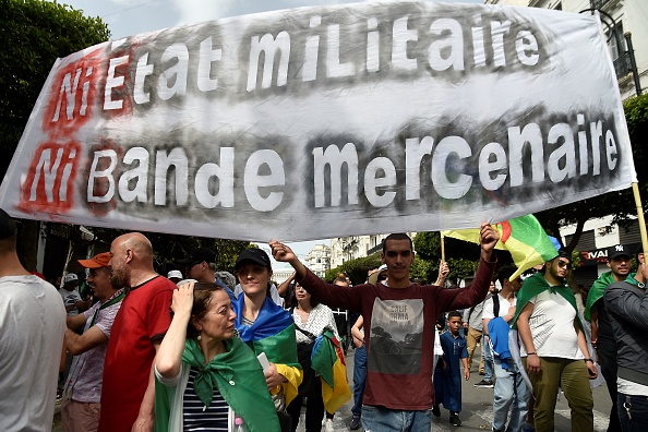 Plusieurs puissants hommes d'affaires ont été placés en détention provisoire depuis la démission le 2 avril de M. Bouteflika, sous la pression d'un mouvement de contestation inédit. Les manifestants algériens tiennent une banderole portant l'inscription "Pas d'état militaire, pas de mercenaires" en manifestant à Alger, le 7 juin 2019.      (Photo : RYAD KRAMDI/AFP/Getty Images)