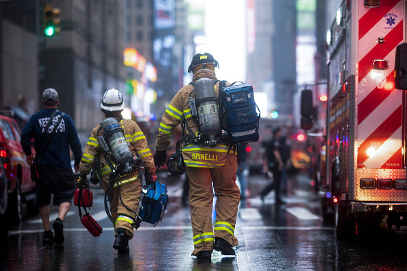 -Les pompiers sont vus près du bâtiment où un hélicoptère s'est écrasé dans le centre-ville de Manhattan, à New York, le 10 juin 2019. -S'exprimant sur les lieux, le gouverneur de New York, Andrew Cuomo, a déclaré aux journalistes qu'il y avait eu "des victimes" à bord de l'hélicoptère, mais qu'aucune personne dans l'immeuble n’avait été blessée. Photo de Johannes EISELE / AFP / Getty Images.