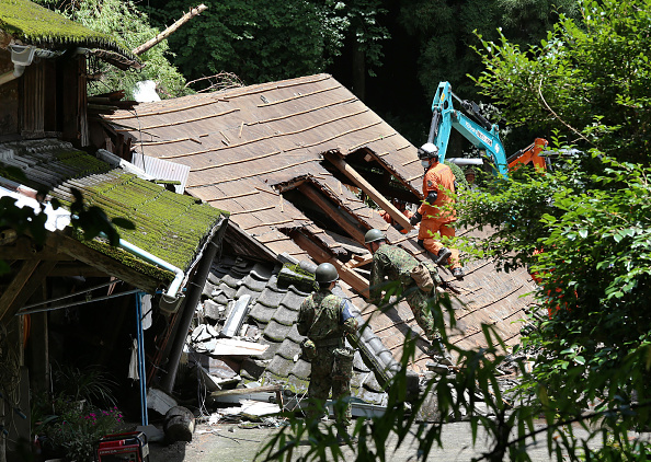 -Des soldats d'autodéfense et des pompiers recherchent un résident disparu dans une maison qui s'est effondrée après un glissement de terrain causé par de fortes pluies dans la ville de Soo, dans la préfecture de Kagoshima, le 4 juillet 2019. Photo par JIJI PRESS / JIJI PRESS / AFP / Getty Images.