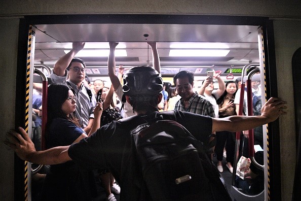 -Un manifestant empêche le train souterrain du MTR de fermer, les manifestants bloquaient les portes du train à la gare de Fortress Hill à Hong Kong le 5 août 2019, dans le but de perturber les trajets quotidiens à l'heure de pointe, pour faire pression sur les dirigeants pro-pékinois du centre financier. Photo par Anthony WALLACE / AFP / Getty Images.