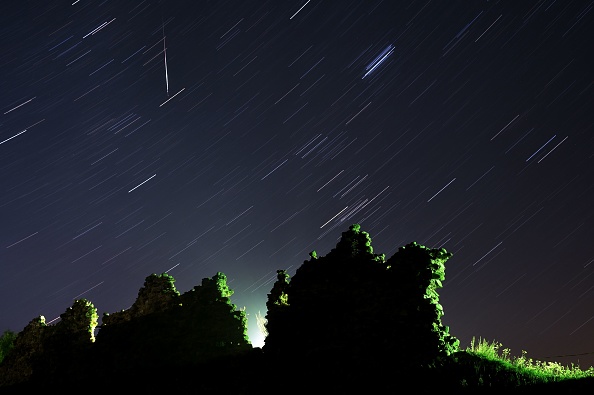 Une météore Perseid traversant le ciel nocturne et des étoiles au-dessus des ruines d'un château médiéval dans le village de Kreva, à environ 100 km au nord-ouest de Minsk, le 12 août 2019.  (Photo :  Sergei GAPON / AFP)        
