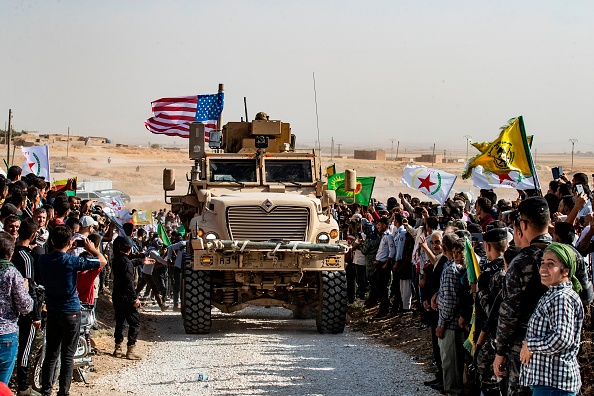 -Des Kurdes syriens se rassemblent autour d'un véhicule blindé américain lors d'une manifestation contre les menaces turques près d'une base de la coalition internationale dirigée par les États-Unis à la périphérie de la ville de Ras al-Aïn dans la province syrienne de Hasakeh, près de la frontière turque, le 6 octobre 2019. Photo de Delil SOULEIMAN / AFP / Getty Images.