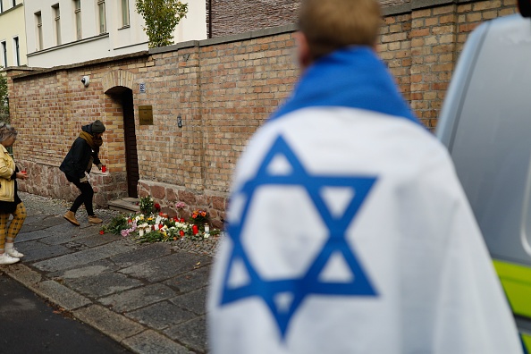 -Les gens déposent des fleurs le 10 octobre 2019 à la synagogue de Halle, dans l'est de l'Allemagne, un jour après l'attaque, où deux personnes ont été abattues. Un des suspects a été capturé, mais à la suite d'une chasse à l'homme pour d'autres auteurs, la sécurité a été renforcée dans les synagogues d'autres villes de l'Allemagne de l'Est. Photo par AXEL SCHMIDT / AFP / Getty Images.
