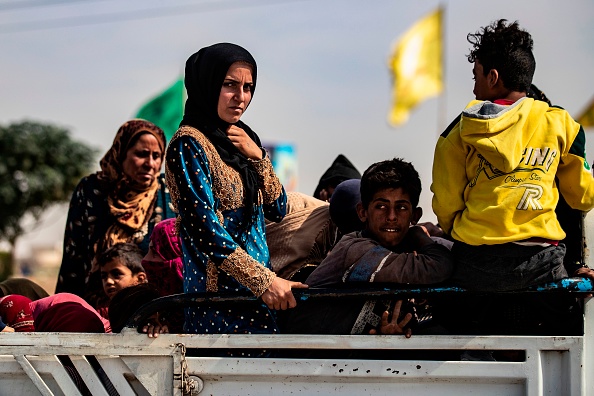 Des Syriens déplacés  assis à l'arrière d'une camionnette pendant que des civils arabes et kurdes s'enfuient face à l'attaque militaire turque contre des zones contrôlées par les Kurdes dans le nord-est de la Syrie, le 11 octobre 2019, dans la ville frontalière syrienne de Tal Abyad. (Photo : DELIL SOULEIMAN/AFP via Getty Images)