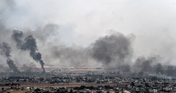 -Cette photo prise le 16 octobre 2019 du côté turc de la frontière dans le district de Ceylanpinar à Sanliurfa montre de la fumée qui monte dans la ville syrienne de Ras al-Ain le huitième jour de l'opération militaire turque contre les forces kurdes. Photo par OZAN KOSE / AFP via Getty Images.