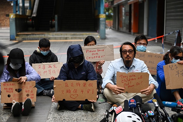 -Des membres de la famille d’étudiants barricadés à l’Université polytechnique de Hong Kong brandissent des pancartes lors d’une manifestation près de l’université à Hong Kong le 19 novembre 2019. Environ 100 manifestants sont restés bloqués à l’intérieur de l’Université polytechnique de Hong Kong. Photo de YE AUNG THU / AFP via Getty Images.