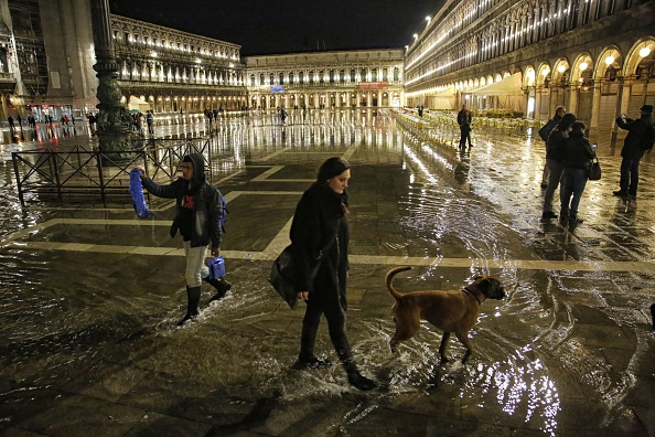 -Les touristes marchent sur la place Saint-Marc inondée au cours de hautes eaux à Venise, dans le nord de l'Italie, le 11 novembre 2016. Photo MARCO BERTORELLO / AFP via Getty Images.