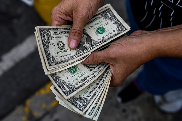 -Un marchand ambulant compte des billets d'un dollar dans une rue de Caracas le 19 novembre 2019. Le président du Venezuela, Nicolas Maduro, a été contraint de relâcher le contrôle des changes et les prix en vigueur pendant les 20 années de chavisme, en raison du manque de liquidités, de l'effondrement du pétrole production et sanctions américaines. Photo de FEDERICO PARRA / AFP via Getty Images.