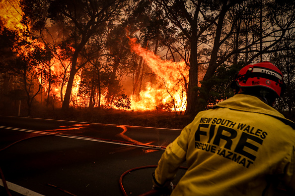 -Illustration- Incendie et sauvetage personnel courir,   des flammes comme un feu de brousse, brûle des arbres le long d'une route près des maisons à la périphérie de la ville de Bilpin le 19 décembre 2019 à Sydney, Australie. Photo de David Gray / Getty Images.