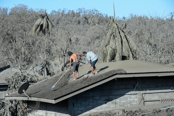 -Les résidents nettoient le toit de leur maison recouverte de boue et de cendres en raison de l'éruption du volcan Taal dans un village de Laurel, dans la province de Batangas, le 16 janvier 2020. Photo de Ted ALJIBE / AFP via Getty Images.