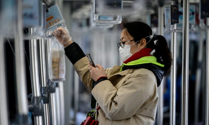 Une femme portant un masque protecteur utilise son téléphone portable alors qu'elle prend le train à Shanghai le 20 février 2020. (Noel Celis / AFP via Getty Images)