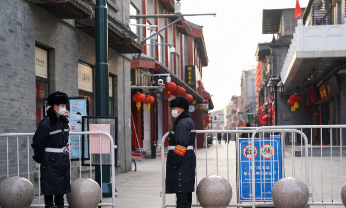 Les gardiens de sécurité chinois portent des masques de protection alors qu'ils se tiennent dans une rue commerciale vide le 25 février 2020 à Pékin, en Chine. (Lintao Zhang / Getty Images)