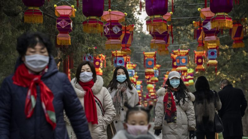 Des habitants portent des masques de protection alors qu'ils marchent sous les décorations du Nouvel An chinois dans un parc de Pékin, en Chine, le 25 janvier 2020. (Kevin Frayer/Getty Images)