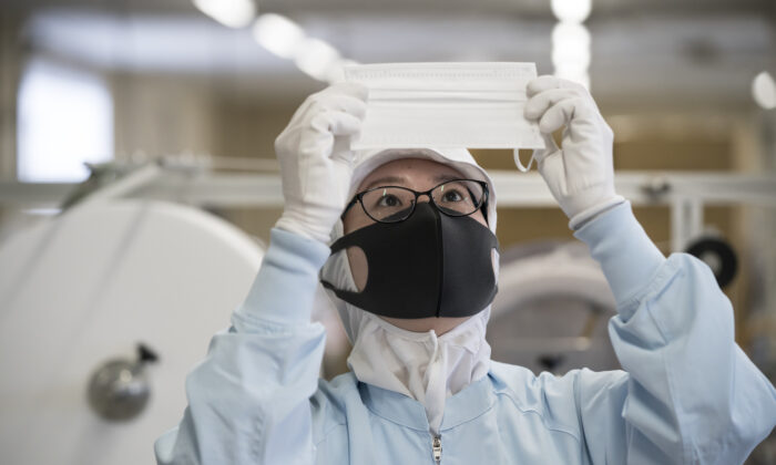 Un employé inspecte un masque facial jetable sur la chaîne de production de la société Yokoi Co. Ltd. à Nagoya, au Japon, le 6 février 2020. (Tomohiro Ohsumi/Getty Images)