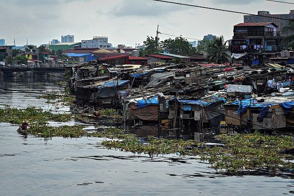 -Un bidonville surpeuplé construit le long d'une rivière polluée à Manille. Photo de Maria TAN / AFP via Getty Images.