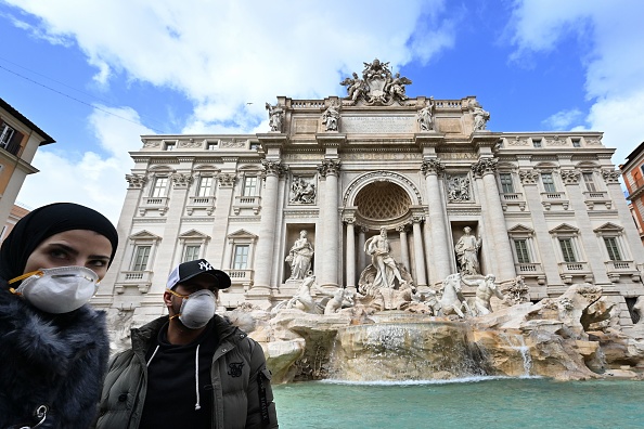 -Les touristes portent des masques de protection devant la fontaine de Trevi au centre-ville de Rome, le 3 mars 2020. Photo par ALBERTO PIZZOLI / AFP via Getty Images.