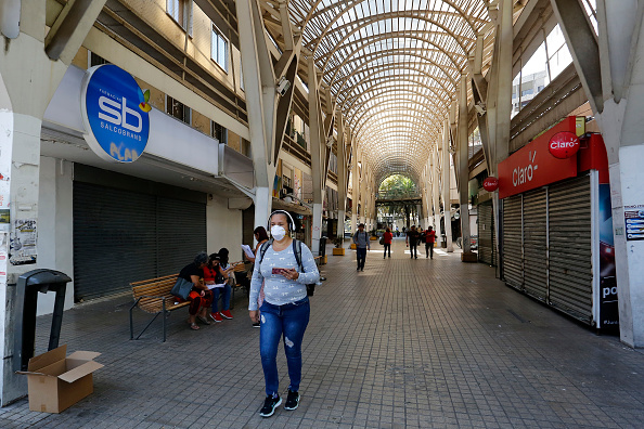 Une femme portant un masque de protection passe devant des magasins fermés lors de la pandémie de coronavirus le 20 mars 2020 à Santiago, Chili. (Photo : Marcelo Hernandez/Getty Images)