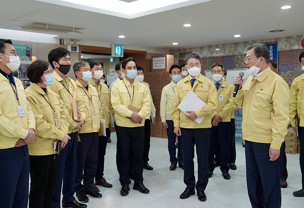 -Le président sud-coréen Moon Jae-in, s'entretient avec des employés du gouvernement lors d'une réunion spéciale pour discuter des mesures visant à empêcher la propagation de COVID -19 à la mairie de Daegu le 25 février 2020 Corée du Sud. Photo de la Maison bleue présidentielle sud-coréenne via Getty Images.