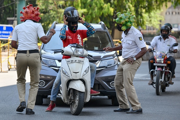 -Le personnel de la police de la circulation porte des casques sur le thème du coronavirus et se produise devant les automobilistes alors qu'ils participent à une campagne pour sensibiliser le public lors d'un verrouillage national imposé par le gouvernement, à Bangalore le 31 mars 2020. Photo de Manjunath Kiran / AFP via Getty Images.