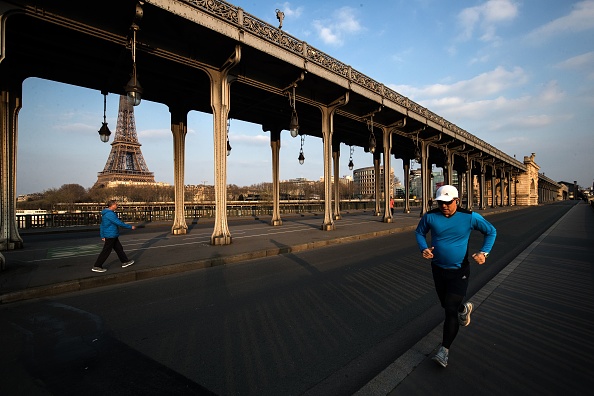 -Des joggeurs courent sur le pont Bir-Hakeim près de la Tour Eiffel à Paris, le 27 mars 2020, le 11e jour d'un verrouillage en France. Photo par JOEL SAGET / AFP via Getty Images.