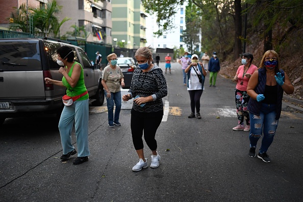 -Les gens dansent lors d'un concert offert par le chanteur vénézuélien Yvanno Pichardo dans la rue du quartier Colinas de Bello Monte à Caracas pour animer le verrouillage du coronavirus COVID-19, le 24 avril 2020. Photo de Federico PARRA / AFP via Getty Images.