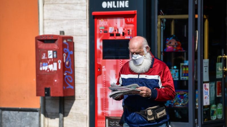 Un résident portant un masque facial sort d'un magasin après avoir acheté un journal à Treviolo, en Italie, le 9 avril 2020. (Miguel Medina/AFP via Getty Images)