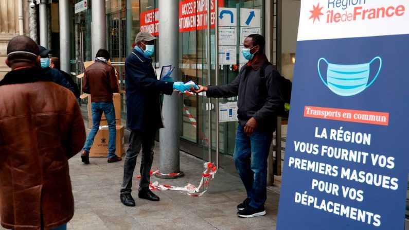 Un bénévole distribue des masques faciaux et des tracts aux voyageurs devant la gare du Nord à Paris le 29 avril 2020. (Photo by THOMAS COEX/AFP via Getty Images)