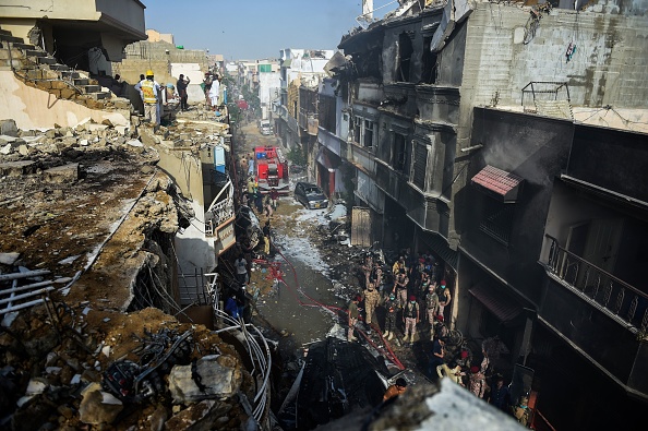 -Des secouristes se rassemblent sur le site après qu'un avion de Pakistan International Airlines s'est écrasé dans une zone résidentielle à Karachi le 22 mai 2020. Photo de RIZWAN TABASSUM / AFP via Getty Images.