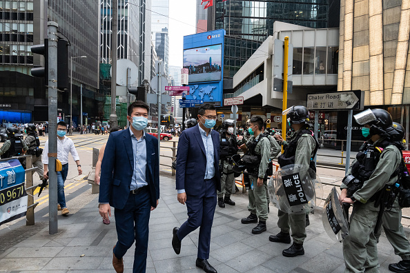 -Des gens passent devant la police anti-émeute le 28 mai 2020 à Hong Kong, Chine. Le Premier ministre chinois Li Keqiang a déclaré vendredi lors de l'Assemblée populaire nationale que Pékin établirait un système juridique solide et un mécanisme d'application pour la sauvegarde de la sécurité nationale à Hong Kong. Photo par Billy HC Kwok / Getty Images.