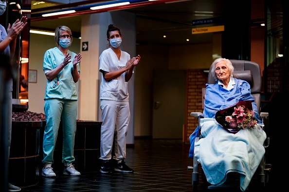 Des travailleurs médicaux applaudissent la patiente belge de 100 ans Julia Dewilde, qui quitte l'hôpital du Bois de l'Abbaye à Seraing, après avoir été traitée avec succès pour le covid-19, le 29 avril 2020. (Photo de Kenzo TRIBOUILLARD / AFP via Getty Images)