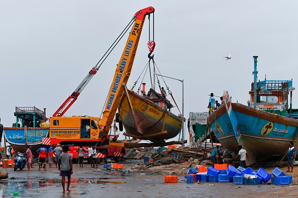 Les pêcheurs regardent une grue soulevant un bateau du rivage par des mesures de sécurité avant un cyclone qui pourrait frapper la côte nord du Maharashtra et du Gujarat, dans le village de pêcheurs de Madh, sur la côte nord-ouest de Mumbai le 2 juin 2020. (Photo : INDRANIL MUKHERJEE/AFP via Getty Images)