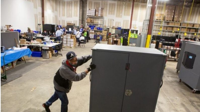 Un employé du comté de Fulton déplace des transporteurs de machines à voter qui seront stockés au centre de préparation des élections du comté de Fulton à Atlanta, Géorgie, le 4 novembre 2020. (Jessica McGowan/Getty Images)