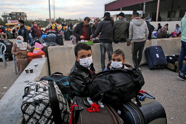 -Des enfants palestiniens masqués attendent dans la zone de départ du poste-frontière de Rafah pour voyager de la bande de Gaza vers l'Égypte, le 9 février 2021. Photo Saïd Khatib / AFP via Getty Images.