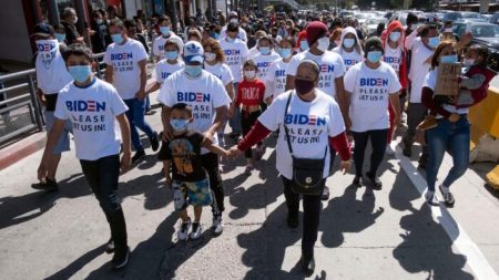 Des migrants photographiés à la frontière entre les États-Unis et le Mexique, portant des t-shirts « M. Biden, s’il vous plaît, laissez-nous entrer »