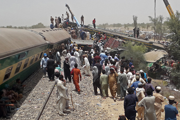 -Le personnel de sécurité et les spectateurs se tiennent sur le site d'un accident de train dans la région de Daharki, le 7 juin 2021. Photo de Shahid ALI / AFP via Getty Images.