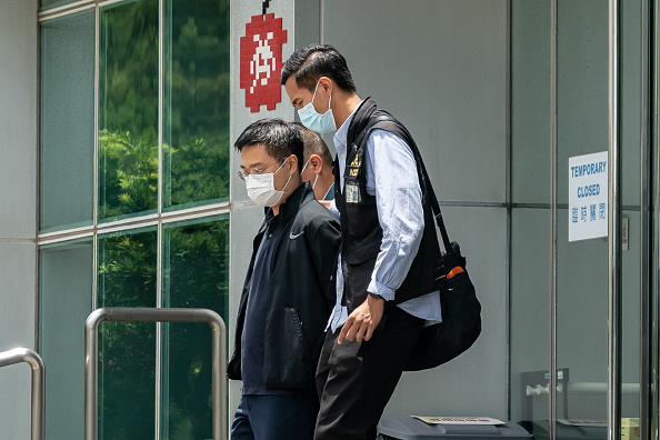 La police escorte Ryan Law, rédacteur en chef, hors du siège du journal Apple Daily, le 17 juin 2021 à Hong Kong. (Photo : Anthony Kwan/Getty Images)