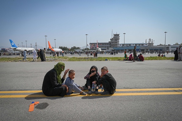 Des Afghans sont assis le long du tarmac alors qu'ils attendent de quitter l'aéroport de Kaboul, le 16 août 2021.(Photo : WAKIL KOHSAR/AFP via Getty Images)