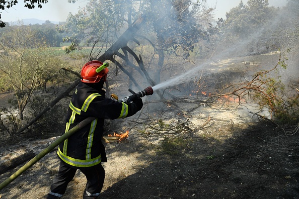 -Un pompier français utilise un tuyau d'arrosage pour tenter d'éteindre les flammes d'un incendie de forêt qui se propage dans la région du Var, dans le sud de la France, le 17 août 2021. Photo de NICOLAS TUCAT / AFP via Getty Images.