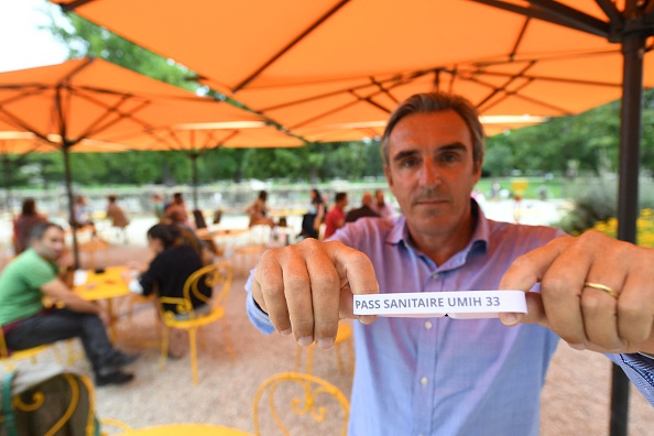 Laurent Tournier, président de l'UMIH 33 (Union des métiers de l'hôtellerie) pose avec un bracelet portant la mention "Pass sanitaire UMIH 33". (Photo : MEHDI FEDOUACH/AFP via Getty Images)