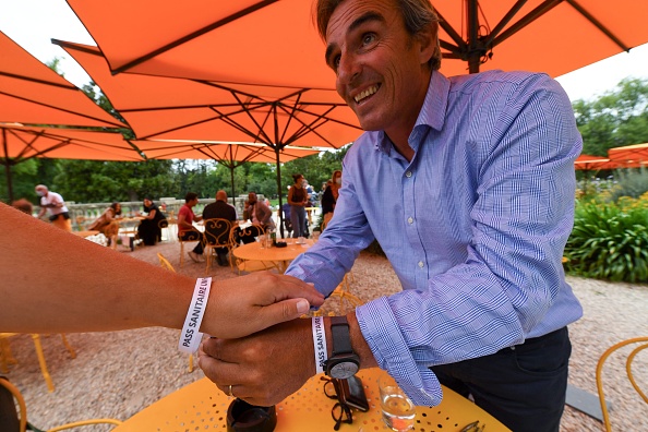 Laurent Tournier, président de l'UMIH 33 (Union des métiers de l'hôtellerie) pose un bracelet portant la mention "Pass sanitaire UMIH 33", au restaurant L'Orangerie à Bordeaux, dans le sud-ouest de la France, le 18 août 2021. (MEHDI FEDOUACH/AFP via Getty Images)