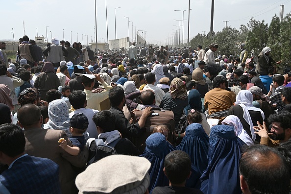 Des Afghans se rassemblent au bord d'une route près de la partie militaire de l'aéroport de Kaboul, le 20 août 2021, dans l'espoir de fuir le pays après la prise de contrôle militaire de l'Afghanistan par les Talibans. (Photo : WAKIL KOHSAR/AFP via Getty Images)