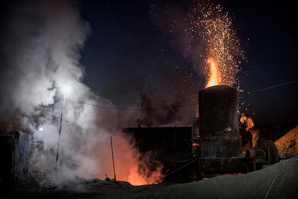 -Un ouvrier chinois charge du charbon dans un four extérieur dans une usine sidérurgique en Mongolie intérieure, en Chine. Photo de Kevin Frayer/Getty Images.