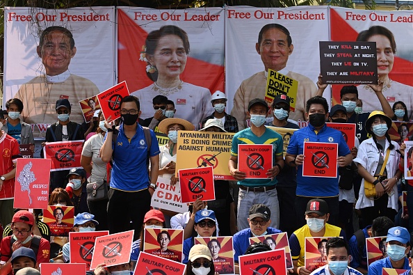 Les manifestants tiennent des pancartes et affichent des images de la dirigeante civile déchue Aung San Suu Kyi et du président Win Myint, lors d’une manifestation devant l'ambassade de Chine à Yangon le 21 février 2021. Photo de Sai Aung Main / AFP via Getty Images.