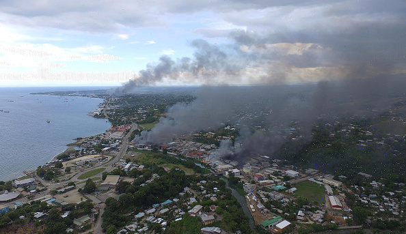 -La fumée des bâtiments en flammes s'élève de Honiara dans les Îles Salomon le 25 novembre 2021, le deuxième jour d'émeutes. Photo Robert TAUPONGI / AFP via Getty Images.