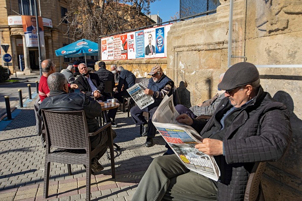 Des gens assis dans un café à côté d'affiches électorales dans la partie nord de Nicosie, le 20 janvier 2022, avant les élections générales. Photo de BIROL BEBEK/AFP via Getty Images.