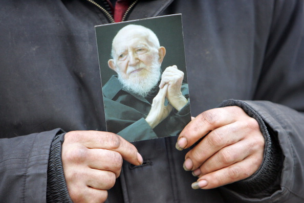 Un sans-abri tient le portrait de l'Abbé Pierre. (MEHDI FEDOUACH/AFP via Getty Images)