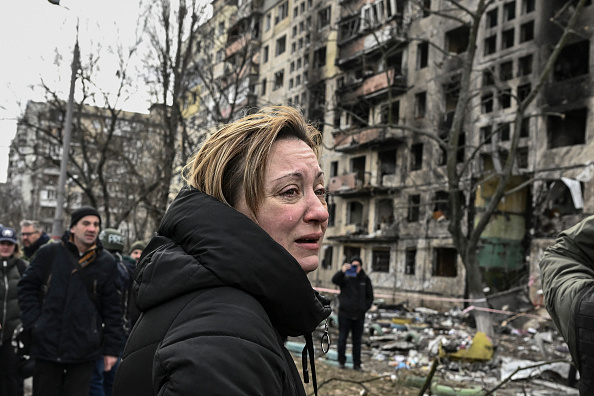 -Une femme pleure alors qu'elle se tient devant des immeubles d'appartements détruits à la suite d'un bombardement à Kiev le 14 mars 2022.  Deux personnes ont été tuées. Photo par ARIS MESSINIS/AFP via Getty Images.