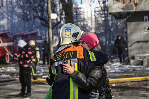 -Un pompier embrasse une femme devant un immeuble endommagé à Kiev le 15 mars 2022, après que des frappes contre des zones résidentielles ont tué au moins deux personnes, Photo par Aris MESSINIS/AFP via Getty Images.